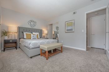 A bedroom with a king sized bed and a door to a bathroom